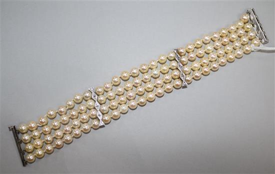 A triple strand cultured pearl bracelet with diamond set white metal clasp and spacers, 19cm.